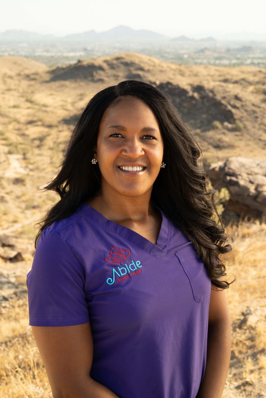 Portrait of Dr. Michelle Perry on South Mountain in Phoenix, wearing purple scrubs embroidered with Abide Physical Therapy Logo